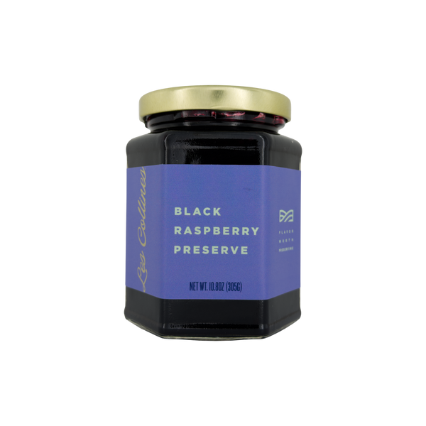 Jar of black raspberry preserve with a purple label on a white background
