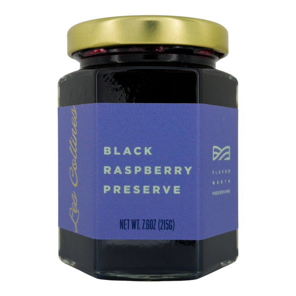 Jar of black raspberry preserve with a blue label on a white background
