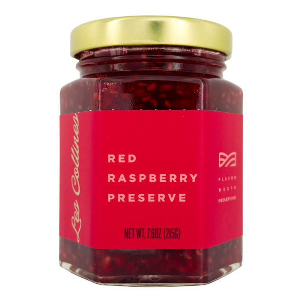 Jar of red raspberry preserve with a gold lid on a white background